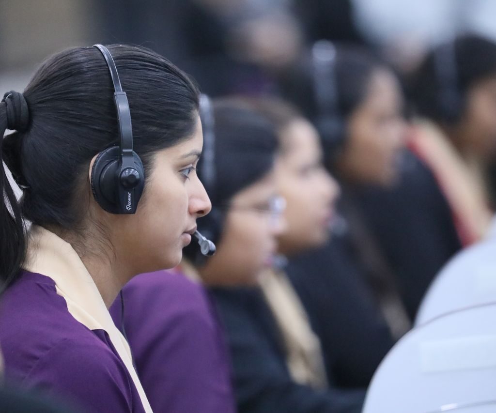 Profile view of a call center agent wearing a headset, focused and working in an office environment.